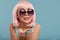 Close up of a flirtatious female model on blue background wearing a pink wig holding different kinds of candies. Pretty