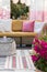 Close-up of flowers on a terrace with a wicker sofa and pillows in the background. Real photo