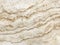 Close up of flowing structure of cream travertine stone with wavy lines across surface. Natural limestone pattern