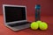 Close up of fluorescent yellow tennis balls by laptop and water bottle