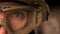Close-up focused eye of strong military man in uniform and helmet, looking at camera while standing, authentic modern