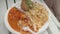 CLose up focused view of disposable plate with Nepalese dish. Hand of person takes food with disposable fork.