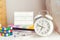 Close up focused white alarm clock with blurred Back to school message hashtag on lightened box, notebooks, rubik`s cube and