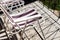 Close up of folding chair on concrete balcony floor with shadows of metal balcony fence. Relaxing on the sun in summer time