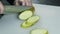 CLOSE UP FOOD: chef chopped green zucchini on a white table with knife