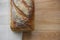 Close up food image of a fresh home made artisan white bread loaf on a cream cloth and wood board background