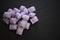 Close up food photography of sugar candy sweets in lilac purple color with floral flavor on black stone background