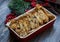 Close up food shot of a pile of sliced dry crunchy Italian Cantuccini Biscotti raisin biscuits in baking paper in a red porcelain