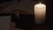 Close up footage of a candle in low light being lit by illuminating books and a woman`s hand leafing through the pages - prores