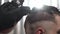 Close up footage clipper shaves the back of the head of a man in a barbershop. Hairdresser or barber in black gloves.