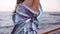 Close up footage of a gorgeous brunette woman in colored silk gown standing near the sea or ocean on a pier. Sensually