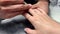 Close up footage of man manicure artist in black t-shirt making woman nail polishing with electric nail file drill tool