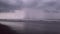 Close-up footage of ocean tide on a dark stormy beach at sunrise. Grey stormclouds and soft glow. Natural seaside