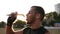 Close up footage of a young male boxer in black bandages has a rest during the training outdoors, drinking water from a