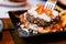 Close up fork pricking Cheeseburger with grilled beef, feta cheese and sliced tomato served with fries in black plate