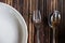 Close-up fork with spoon and white dish on wooden tablemat