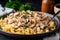 Close-up of a fork twirling strands of homemade egg noodles covered in creamy beef stroganoff sauce, garnished with fresh chives