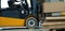 Close up of forklift working in warehouse. Industrial lift truck, jitney lifting and moving materials in factory
