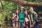 Close up of four cheerful friends in the summer nice wood. They are tourists in a vacation, posing for portrait in a sunny summer