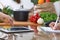 Close-up of four human hands are gesticulate over a tablet in the kitchen. Friends having fun while choosing menu or