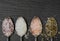 Close-up of four silver teaspoons lying on a black slate plate and in which various salt mixtures and salt crystals lie in the