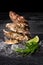 A close-up of four tasty fresh oysters with ice cubes and sliced lime on a black background. Delicious tropical sea mollusk.