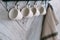 Close up, four white cups and blurred towel hang on hooks on kitchen wall