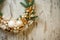 Close-up of fragment of Christmas wreath of white vine decorated with fir branches, balls and bows