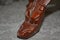 Close-up of a fragment of a wooden vase. A beast`s head carved out of wood and varnished.