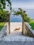 Close up framed view of stairs leading through doorway and orange dog at the end .Orange dog walking near the blue sea. Green gar