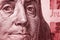 Close-up of Franklin`s face on a fragment of a 100 USD note. Red toned illustration on the financial theme of the American dollar