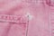 A close-up of a frayed pink jeans pocket, a torn off pocket