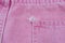 A close-up of a frayed pink jeans pocket, a torn off pocket
