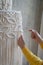 Close up of freelancer woman working on half-finished macrame piece, weaves lamp shade for chandelier. Women hobby