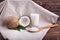 Close-up of fresh bright brown coconuts, organic coco milk, and a wooden spoon with coconut chips on a dark wooden