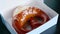 Close Up of Fresh Brown Pretzel with Sea Salt in White Paper Box in Pastry Shop