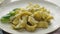 Close up of fresh cooked tagliatelle pasta with green pesto and herbs