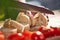 Close-up of fresh crusty bread slices on table. Woman`s hand cutting, slicing bread on wooden board in kitchen. Cooking, food and