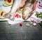 Close up of fresh fish with cooking ingredients on rustic background, top view.