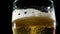 Close-up of fresh frothing light beer in a glass on a dark background