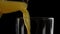 Close-up of fresh orange juice pouring from decanter in a tall glass in slow motion against background