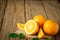 Close-up of Fresh oranges, half-cut fruit, slice with green leaves on an old wood vintage table.