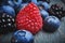 Close up fresh raspberrie, blueberries and blackberryes on a dark background