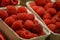 Close-up of fresh red ripe raspberry berries in organic container boxes on the table of farmers market