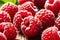 Close-up of fresh, ripe, red raspberries on wooden table with green leaves