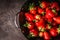 Close up of fresh strawberries in black colander bowl, top view