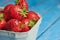 Close up of fresh strawberries in a cardboard box against blue background