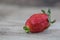 Close-up of fresh strawberry with tip looks like lips on wooden background. Love, kiss, lip care concept