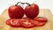 Close up of Fresh Tomatoes with Slices on Wooden Board