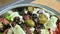 Close-up of fresh vegetarian veggie Greek salad feta paprika tomato olives and spices. Shallow depth of field